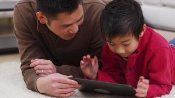 pai e filho usando um tablet digital juntos video