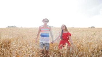 giovani coppie felici che camminano insieme attraverso il campo di grano