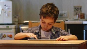 uma criança fofa usa um tablet pc em uma mesa