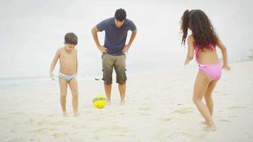 Family plays soccer together on a beach