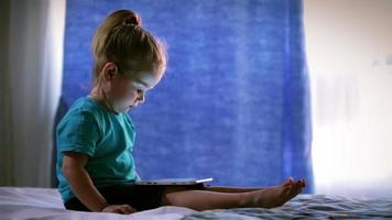 jolie petite fille utilise un tablet pc, touche l'écran du doigt video