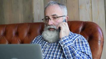 Hombre barbudo senior adulto hablando por un teléfono inteligente video