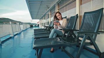 Femme à l'aide de tablette sur le pont du bateau de croisière au lever du soleil