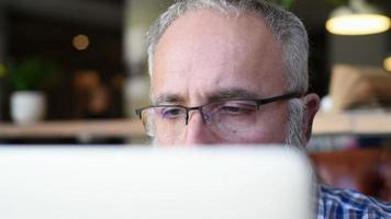 Adult senior bearded man sitting with a laptop video