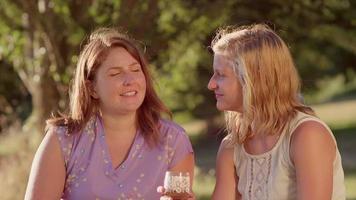 Two young women sharing drinks together in the park video