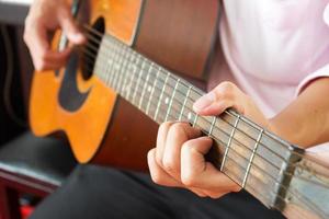 Primer plano las manos del hombre tocando la guitarra clásica.