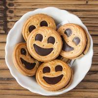 Round smiling chocolate cookies in a bowl over wooden background photo