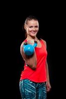 Fitness young woman in red shirt standing with kettlebells on