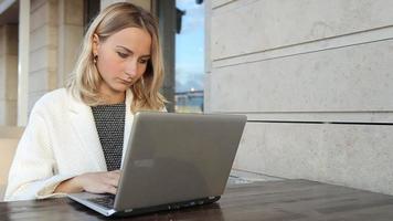 Woman online shopping via laptop in cafe video