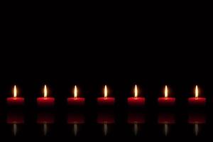 Burning red candles in front of black background photo