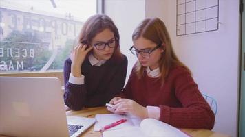 Estudiantes universitarias estudiando en el café dos amigas aprendiendo juntas video