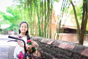 Cute little Asian girl in dress holding a red rose  photo