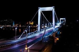Senderos de semáforo en un puente blanco en la noche foto