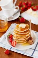 Pancakes with strawberry, butter and honey syrup photo