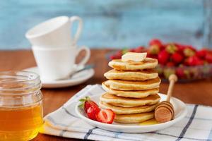 Pancakes with honey syrup, butter and strawberry photo