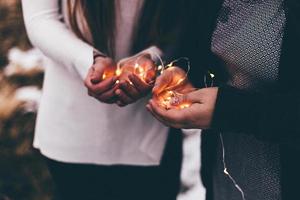 Close-up of two people holding illuminated string lights photo