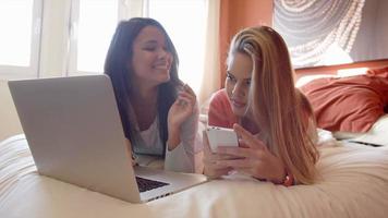 filles discutant sur ordinateur portable en position couchée sur le lit
