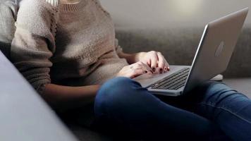 Woman sitting in sofa and working on laptop video
