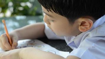 criança asiática sorridente estudando e fazendo sua lição de casa