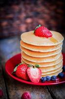 Homemade pancakes with strawberries,blueberries and maple syrup on background photo