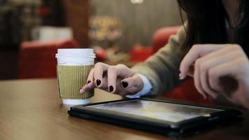 Manos de mujer con pantalla táctil de tableta en café