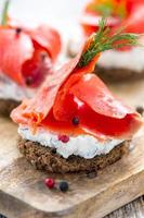 Sandwich of black bread, cheese with herbs and red salmon. photo