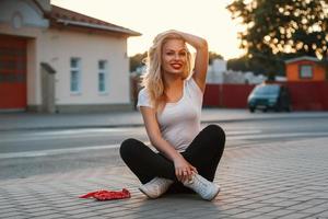 Beautiful girl sitting on the asphalt near a road photo