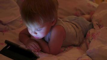 een kleine jongen kijkt laat in de avond naar tekenfilms op de smartphone video