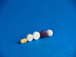 Pills in a row on blue background photo