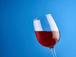 Copa de vino tinto sobre fondo azul. foto