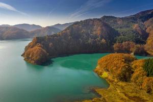 Montaña junto al lago azul bajo un cielo azul durante la temporada de otoño foto