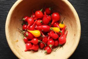 Red and yellow pimentos biquinhos in a wooden bowl. photo