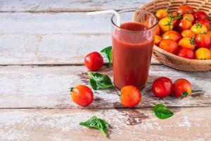 jugo de tomate fresco con tomates en una canasta foto