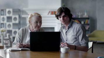 kleinzoon die grootmoeder leert hoe ze een laptop moet gebruiken. ze glimlachen en lachen