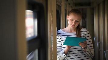 Mujer joven con almohadilla de pie junto a la ventana en tren video