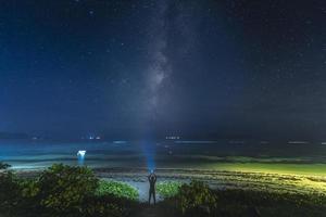 persona de pie con luz estroboscópica bajo la vía láctea foto