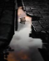 Puddle reflection of plastic waste in cobblestone street photo