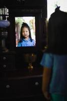 Little girl smiling and looking in the mirror photo