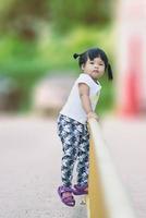 niña subiendo valla amarilla en el parque foto