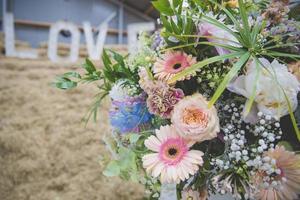 Close up on colorful pastel flower bouquet with LOVE letters in the background