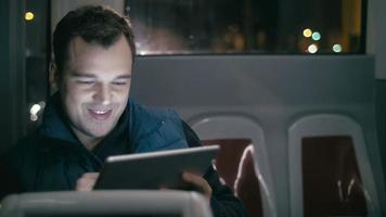 lachende man in de bus met tabletcomputer