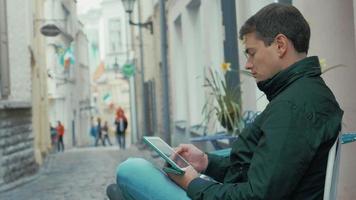 Hombre adulto con tablet PC sentado en la calle