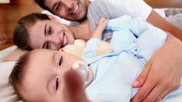 glückliche Eltern, die mit dem kleinen Sohn auf dem Bett liegen video