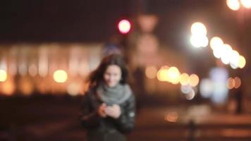 hübsche junge Frau, die fröhlich auf der Straße geht, SMS, mit einem Smartphone. dann geht sie weg. Moderne Technologie