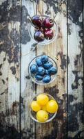 cherries, apricots, currants in a bowls, on a wooden background,