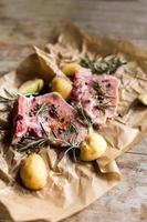 Raw meat with potatoes and herbs on wooden table photo