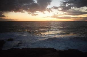 Ocean waves crashing on rocks during sunset