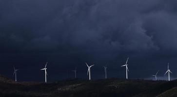 Wind turbines on hill under gray sky