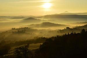 Hazy yellow sky with silhouetted mountains photo