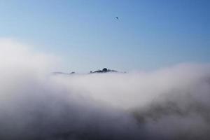 Band of fog rolling through landscape under blue sky photo